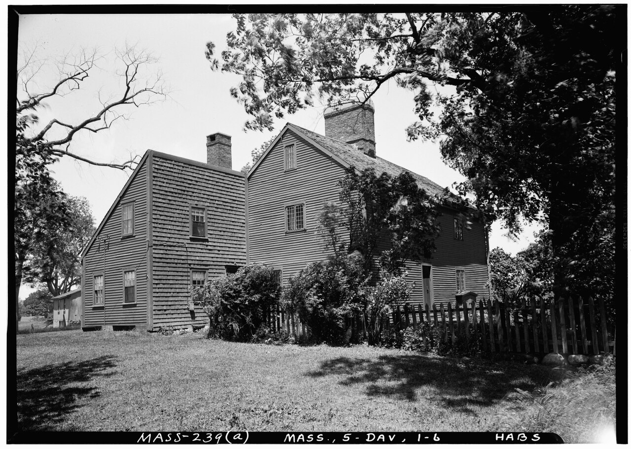 The Nurse farmhouse, a two-storey clapboard house with a central chimney, behind a picket fence